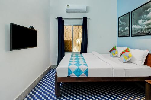 a bedroom with a bed with a tv and a window at OYO Nilay Guest House in Behāla