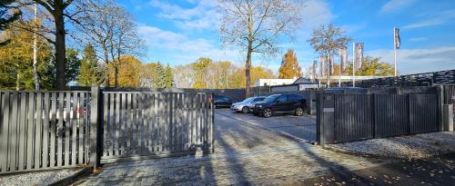 a parking lot with cars parked next to a fence at Triumph Ferienhäuser & Apartments in Rangsdorf