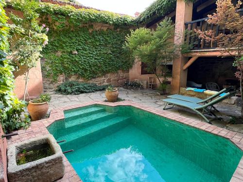 Una piscina en un patio trasero con una silla y una mesa. en La Casa del Bosque, en Cabra de Mora