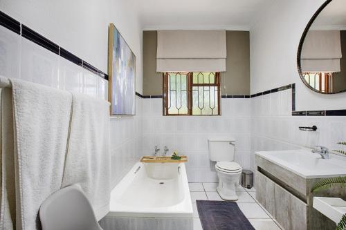 a white bathroom with a toilet and a sink at The River Guestroom in Krugersdorp
