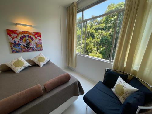 a bedroom with a bed and a window and a couch at STUDIO12 in Petrópolis