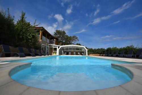 une grande piscine avec des chaises et un bâtiment dans l'établissement Résidence Chiar' Di Luna, à Sainte-Lucie de Porto-Vecchio