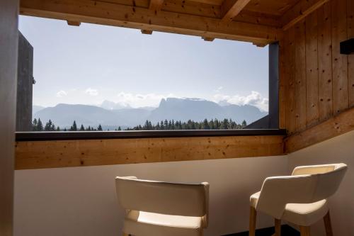two chairs in front of a large window with mountains at Hotel Tann in Collalbo