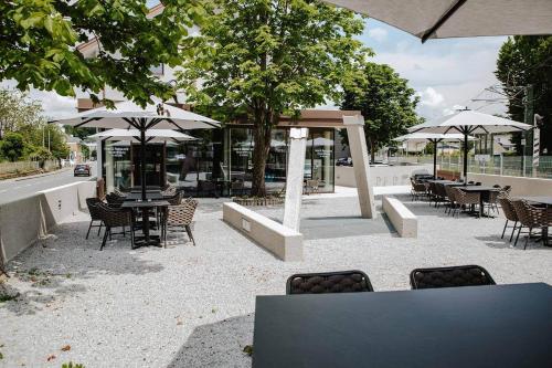 een patio met tafels, stoelen en parasols bij Hotel Gleiserei in Oberndorf bei Salzburg