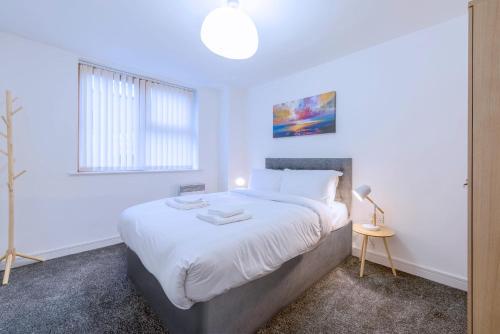 a white bedroom with a large bed and a lamp at 2Bed Homely Hideout in City Centre in Manchester