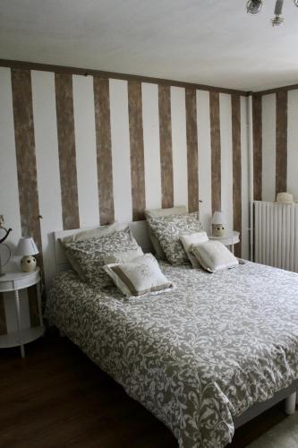 a bedroom with a bed with a striped wall at Chambres à la maison Hermitage in Aincourt