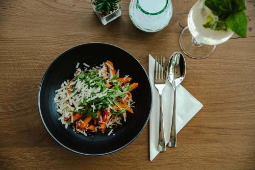 a black bowl of food with rice and vegetables on a table at Hotel Gleiserei in Oberndorf bei Salzburg