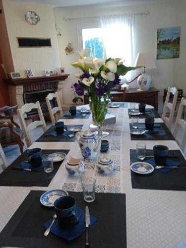 une table de salle à manger avec un vase de fleurs dessus dans l'établissement Les Hortensias, à Saint-Pierre-de-Plesguen