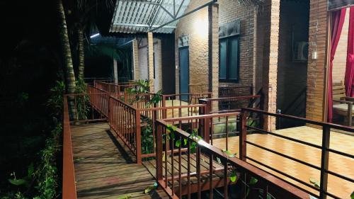 a wooden walkway leading to a house with a balcony at Gibbon Singing Home Stay in Quan Tom