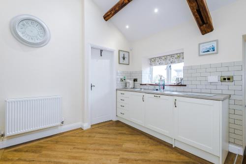 a kitchen with white cabinets and a clock on the wall at Stunning 3-bed cottage in Beeston by 53 Degrees Property, ideal for Families & Groups, Great Location - Sleeps 6 in Beeston