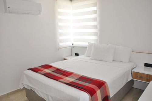 een witte slaapkamer met een bed en een raam bij Hisar Prestige D in Fethiye