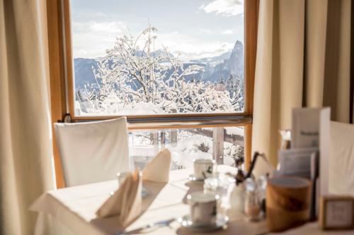 a table with a view of snow covered trees from a window at Hotel Tann in Collalbo