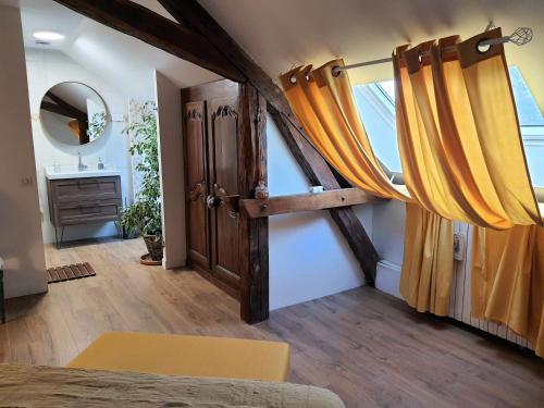 a bedroom with a wooden door and yellow curtains at Le Cèdre 