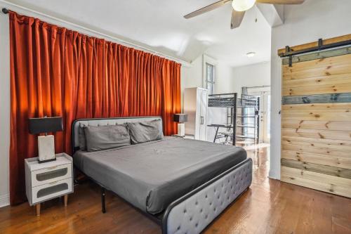 a bedroom with a bed with an orange curtain at GrandCraftsman style home with pool and hot tub/ center to all of New Orleans in New Orleans