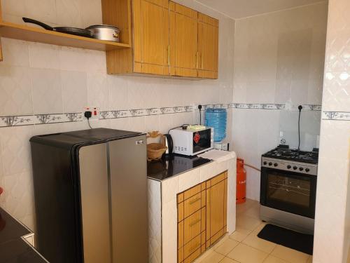 a small kitchen with a refrigerator and a microwave at Wike Suites in Nakuru