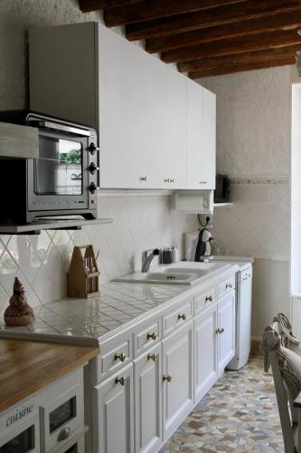 a kitchen with white cabinets and a microwave at Chambres à la maison Hermitage in Aincourt