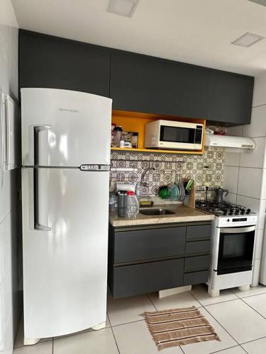 La cuisine est équipée d'un réfrigérateur blanc et d'un four micro-ondes. dans l'établissement Apto melhor localização do Cocó, à Fortaleza