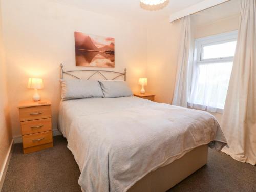 Un dormitorio con una cama y dos lámparas y una ventana. en 2 Bryn Hyfryd, en Abersoch