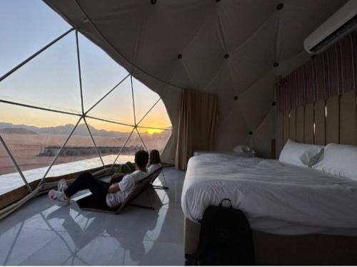 twee personen in een kamer met een bed en een raam bij camp scylla Wadi Rum in Wadi Rum