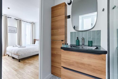 une salle de bain avec un lavabo, un miroir et un lit dans l'établissement MyKeypers - Amazing Luxe & Cosy Flat 2BR/6P - Bastille, à Paris