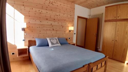 um quarto com uma cama azul e uma parede de madeira em Casa Micéi em Tesero