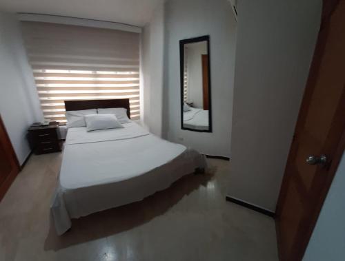 卡利的住宿－Hotel Ciudad Capri，卧室配有白色的床和镜子
