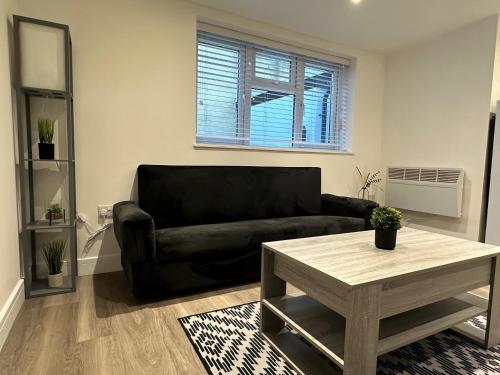 een woonkamer met een zwarte bank en een tafel bij One Bedroom Apartment in Luton Town Centre in Luton