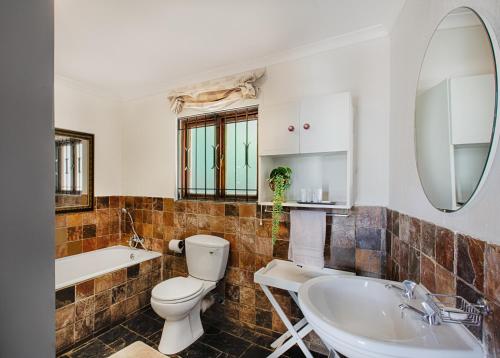 bagno con servizi igienici, lavandino e specchio di The River Cottage a Muldersdrift