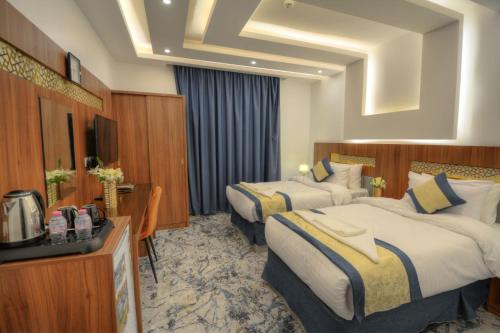 um quarto de hotel com duas camas e uma televisão em فندق المرزم-Al Marzam Hotel em Medina
