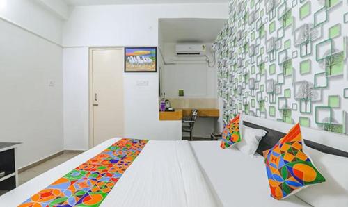 a bedroom with a large white bed with colorful pillows at FabExpress Ashiyana Inn in Patna