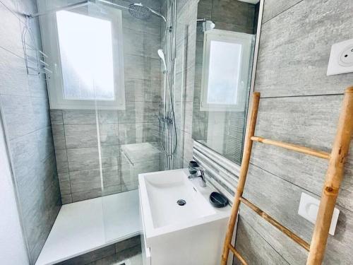 een badkamer met een witte wastafel en een douche bij Le Bernou : Hypercentre- calme et unique! in Saint-Étienne