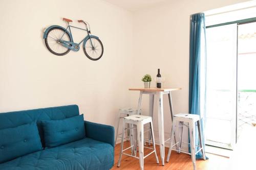 a blue couch in a living room with a bike on the wall at Lisbon Historic Center Apartment in Lisbon