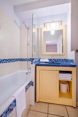 une salle de bain avec une baignoire, un lavabo et un miroir dans l'établissement Résidence Pierre & Vacances Heliotel Marine, à Saint-Laurent-du-Var