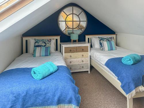 two twin beds in a attic bedroom with blue walls at Crab Cottage in Morfa Nefyn