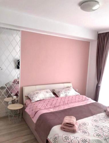 a bedroom with a bed with a pink wall at Happy Residence Sibiu in Sibiu