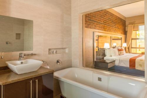 een badkamer met een wastafel en een bed met een spiegel bij Exquisite executive room for 2 - 2179 in Kingsmead