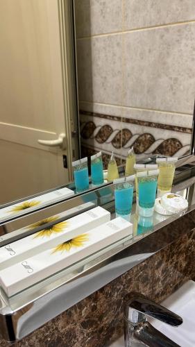 een badkamerbar met enkele glazen en een spiegel bij روز للشقق الفندقية 3 in Hotat bani tamim