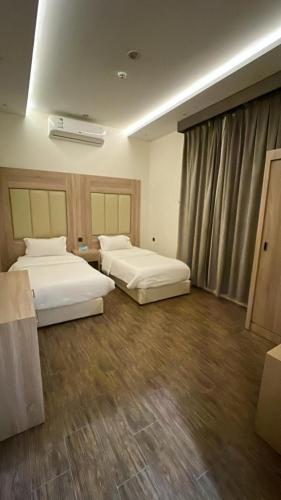 een hotelkamer met 2 bedden en een raam bij روز للشقق الفندقية 3 in Hotat bani tamim