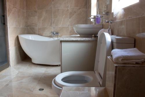 a bathroom with a toilet and a sink and a tub at Deluxe room on a resort - 2182 in Kingsmead