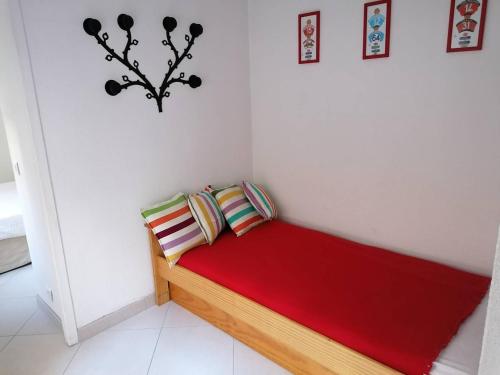 ein kleines rotes Bett in einem weißen Zimmer in der Unterkunft Saint-Jean de Luz, T2 bis terrasse 3 couchages in Sainte-Barbe