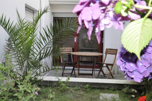 einen Tisch und Stühle in einem Garten mit lila Blumen in der Unterkunft Saint-Jean de Luz, T2 bis terrasse 3 couchages in Sainte-Barbe