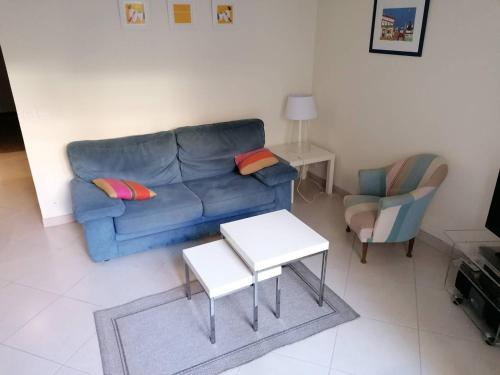 ein Wohnzimmer mit einem blauen Sofa und 2 Stühlen in der Unterkunft Saint-Jean de Luz, T2 bis terrasse 3 couchages in Sainte-Barbe