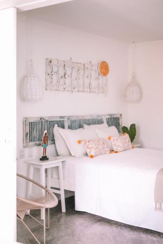a white bedroom with two beds and a chair at Cactus Lodge Pipa in Pipa