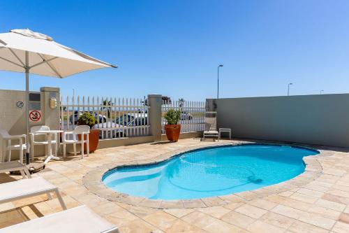 a swimming pool on a patio with an umbrella at Mouille Point Places - Studios & Apartments in Cape Town