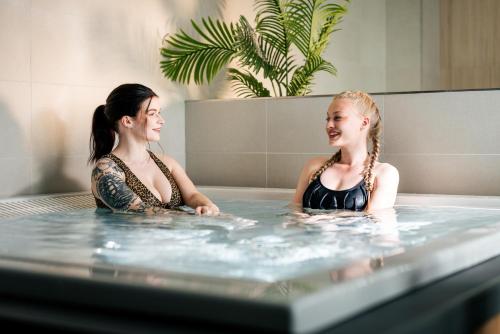 拉彭蘭塔的住宿－Hotelli Lähde，两名妇女坐在热水浴缸中