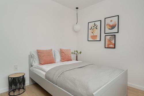 Dormitorio blanco con cama con almohadas de color naranja en Elegant Apartment for 4 with Parking in Poznan by Renters, en Poznan