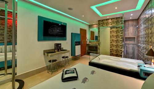 a large bathroom with a tub and a sink at Motel Deslize Ribeirão Preto in Ribeirão Preto