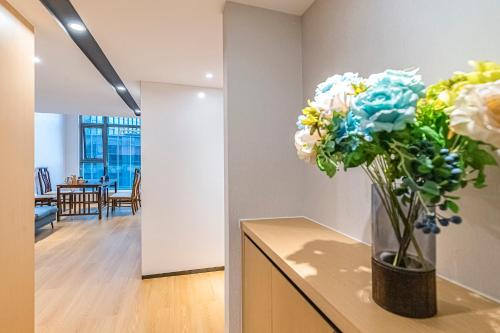 a vase of flowers sitting on a counter in a room at Kunming Dianchi Mideel International Apartment - South Asian Style Fuhai Metro in Kunming