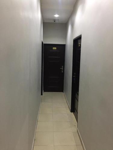 a hallway with a black door and a tile floor at House One Apartment in Mgbu-Oba