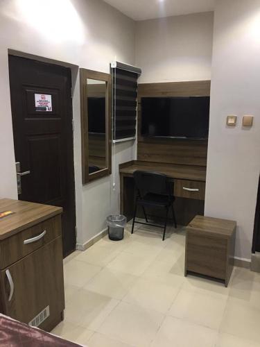 a room with a desk and a chair and a television at House One Apartment in Mgbu-Oba